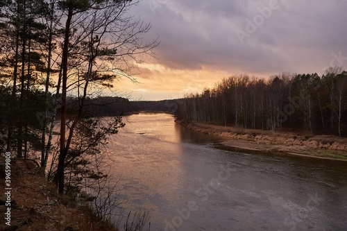 River landscape with colorful twilight sky and woods on the riverside