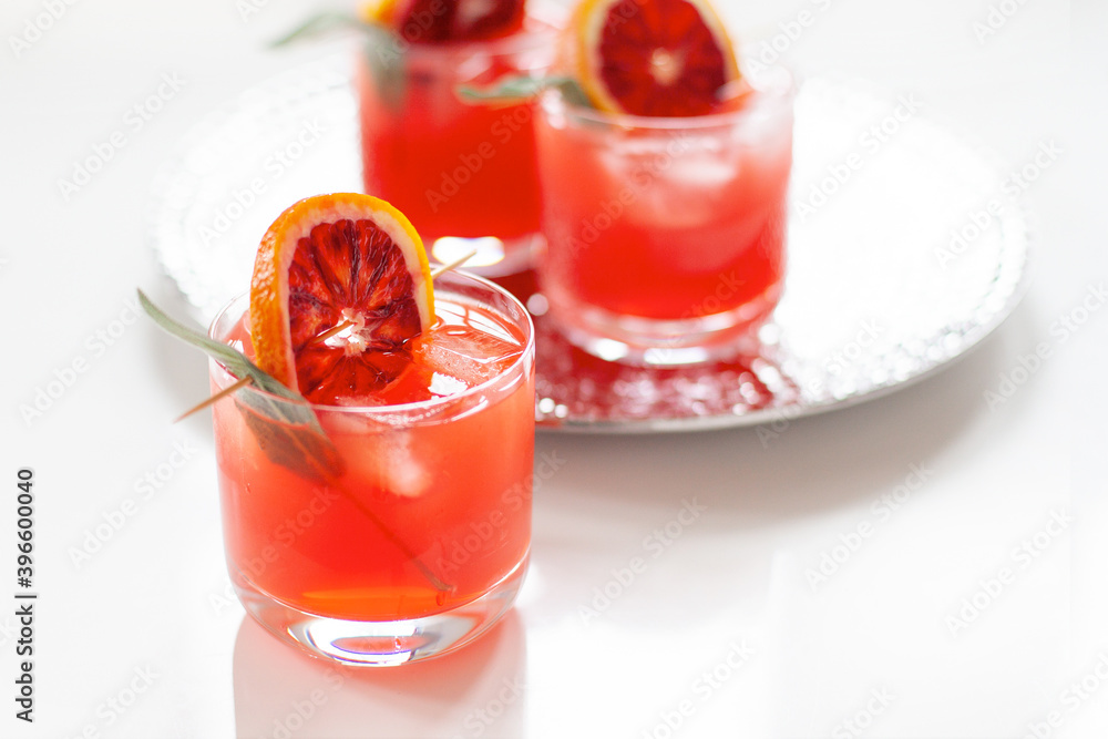 Blood orange cocktails with sage on white minimal background Blood orange cocktails with sage on white minimal background