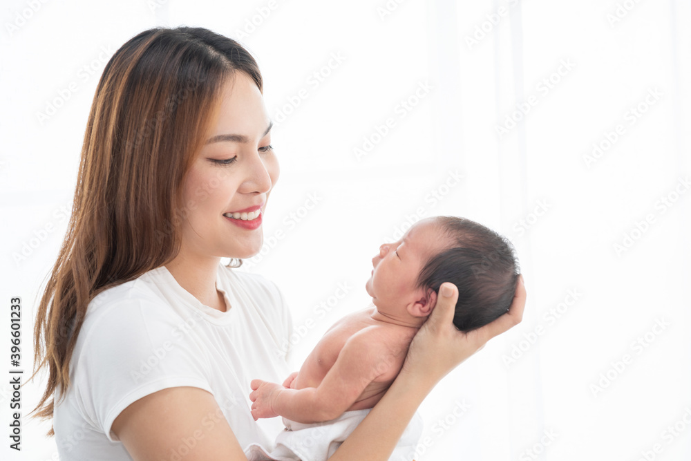 Pretty asian woman smile and holding a newborn baby in her arms. Happy family. Asia mother lifting and looking her adorable infant baby on white. love people concept Pretty asian woman smile and holding a newborn baby in her arms. Happy family. Asia mother lifting and looking her adorable infant baby on white. love people concept