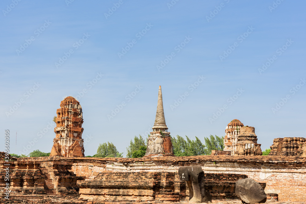 An ancient pagoda in an old temple and a very old brick wall in Ayutthaya, Thailand.