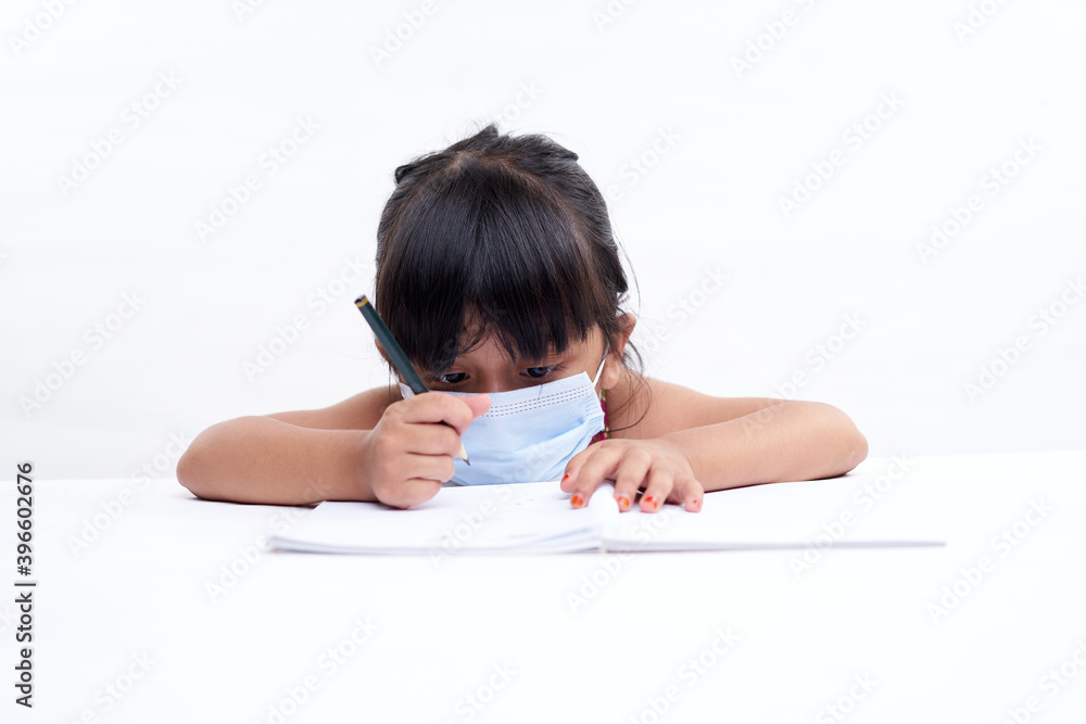 Cute little girl writing in notebook Wearing a protective face mask, Homeschooling New Normal education concept