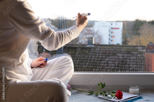 a girl sits on the windowsill and writes something on the window glass photo