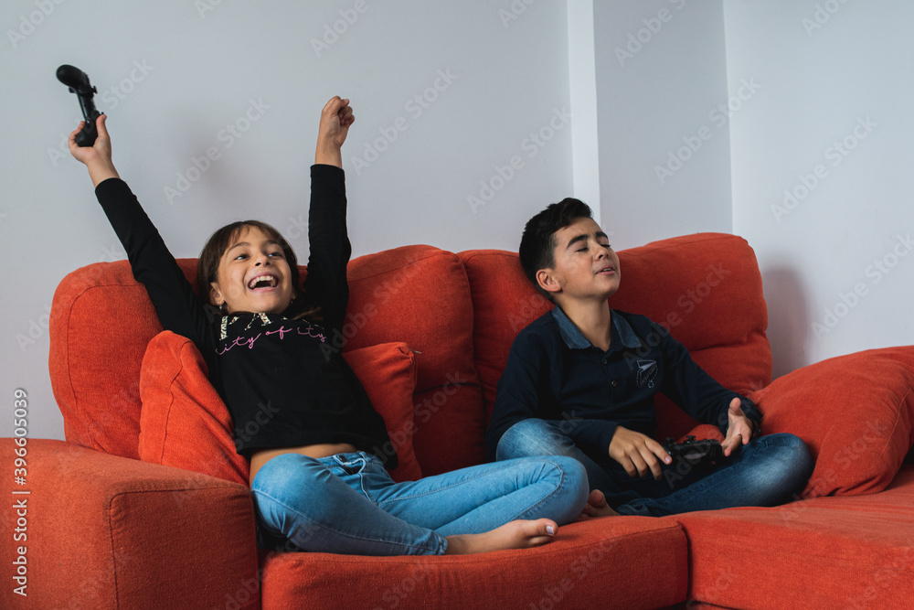 Two children sitting on the sofa at home playing video games. Two children sitting on the sofa at home playing video games.