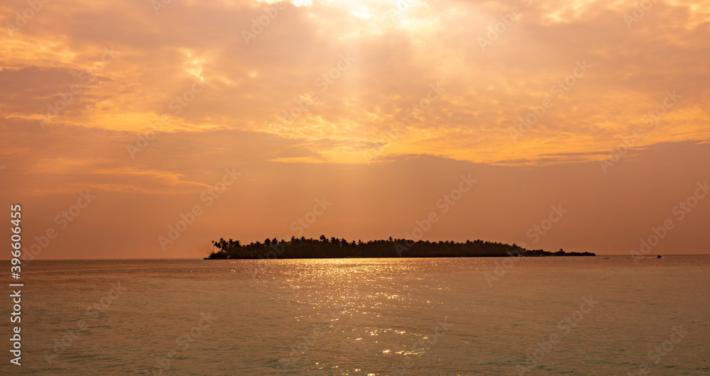 Sun rays in sunset sky on tropical island. Relaxing vacation at the Maldives.