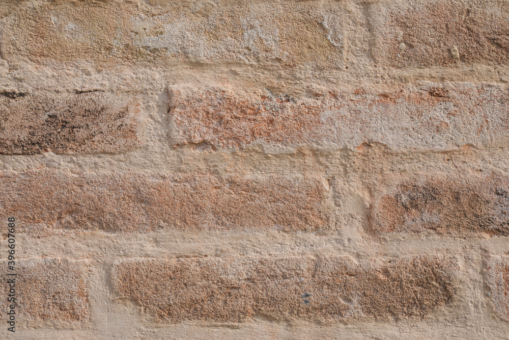 Fototapeta premium Uneven brick wall with cracked bricks, wall empty with space for text and a background