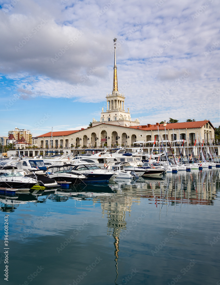 Fototapeta premium Sochi, Russia - November 23, 2020: Sochi, Russia - November 23, 2020: Sochi Commercial Sea Port. Main building of Marine Station. Motor ships and yachts on marinas. Close-up. Calm Black Sea.