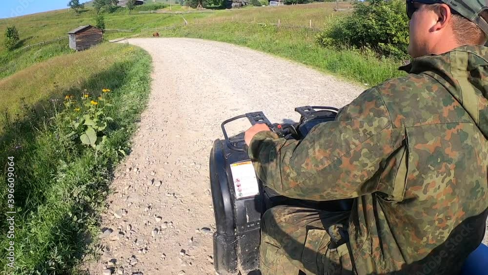 Man rides a quad bike on a dirt road at the top of a mountain Man rides a quad bike on a dirt road at the top of a mountain