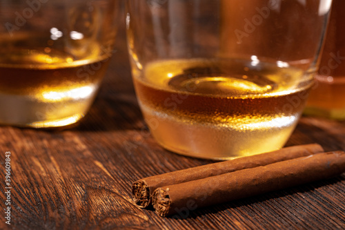 Two glasses of whisky and cigars on wooden table