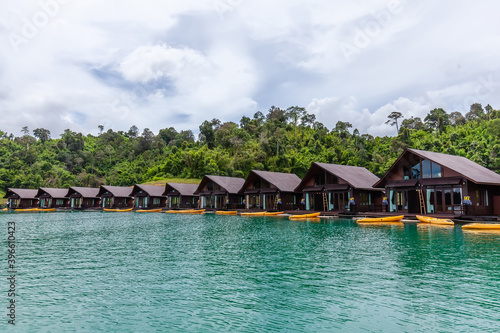 Luxury Resort with Floating Raft Houses with Kayaks on Green Lake with Tropical Trees. Traditional Thai Bungalows at Cheow Lan Lake, Ratchaprapha Dam, Khao Sok National Park in Thailand, Surat Thani
