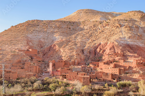 Sunset over a Moroccan typical village built on the foothills of the mountain, in a green valley, with buildings made out of clay, in the southern High Atlas mountains