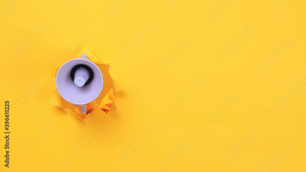 Woman hand arm hold megaphone isolated through torn yellow background. Copy space advertisement place for text image workspace mock up Hot news announce discounts sale hurry up communication concept
