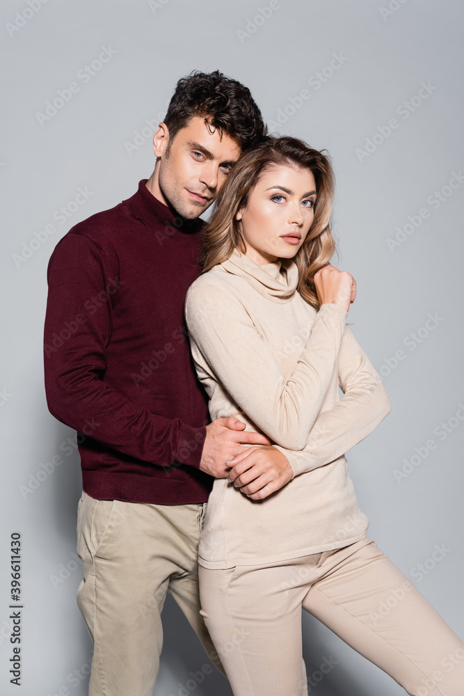 young couple in turtleneck jumpers embracing isolated on grey young couple in turtleneck jumpers embracing isolated on grey
