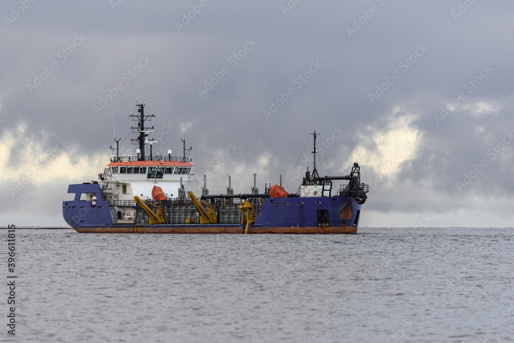 Vessel engaged in dredging. Dredger working at sea. Ship excavating material from a water environment.