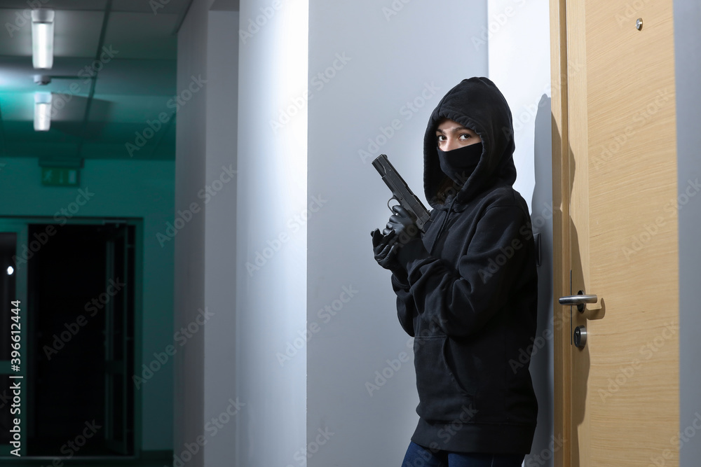 Thief broke into the apartment. House robbery by woman in a black jacket and black mask black gun and crowbar. Burglar in a mask. Thief in a mask trying to break into other people's house. Thief broke into the apartment. House robbery by woman in a black jacket and black mask black gun and crowbar. Burglar in a mask. Thief in a mask trying to break into other people's house.