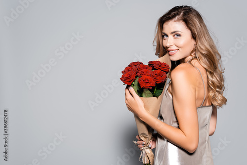  elegant woman in dress with bouquet of red roses isolated on grey