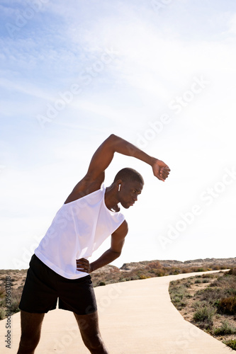 Vertical Middle shot of young black sports trainer doing stretching and warm-ups before training. Concept of health.