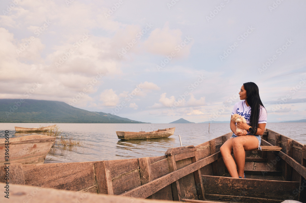 Woman sitting on boat holding a french poodle mini puppy in lake Managua, Nicaragua