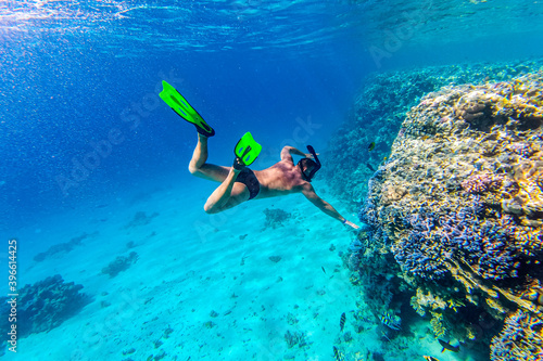Snorkeler and coral reef. Snorkeler in the deep blue sea. Life underwater near the coral reef. Man snorkeling in mask. Freediving sport activity. Underwater shooting