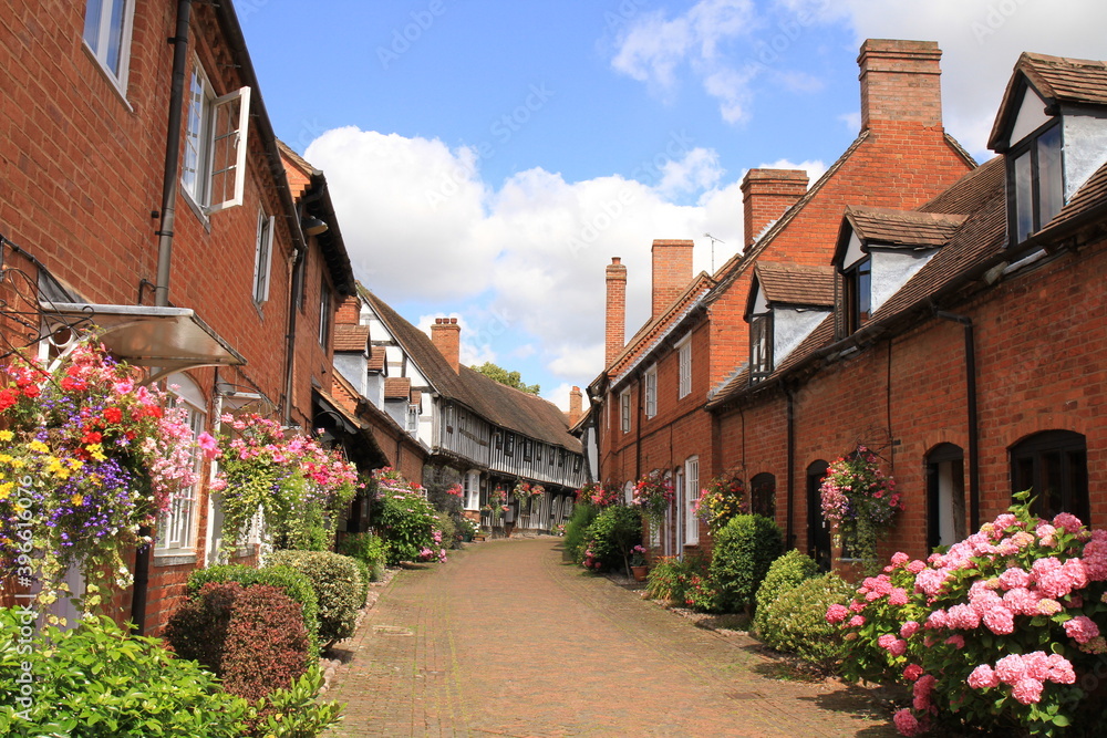 Brick and Half Timbered Houses in Shakespeare's Country Malt Mill Lane Alcester Warwickshire, UK. With hanging baskets & floral blooms in High Summer.