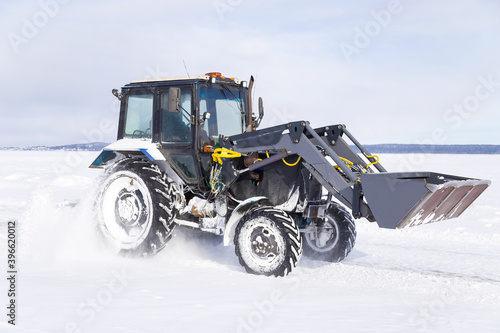 Snow removal vehicle on the road. Snow plow tractor is cleaning a city embankment after snowstorm in winter