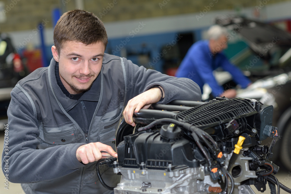auto mechanic shows trainee maintenance of car engine