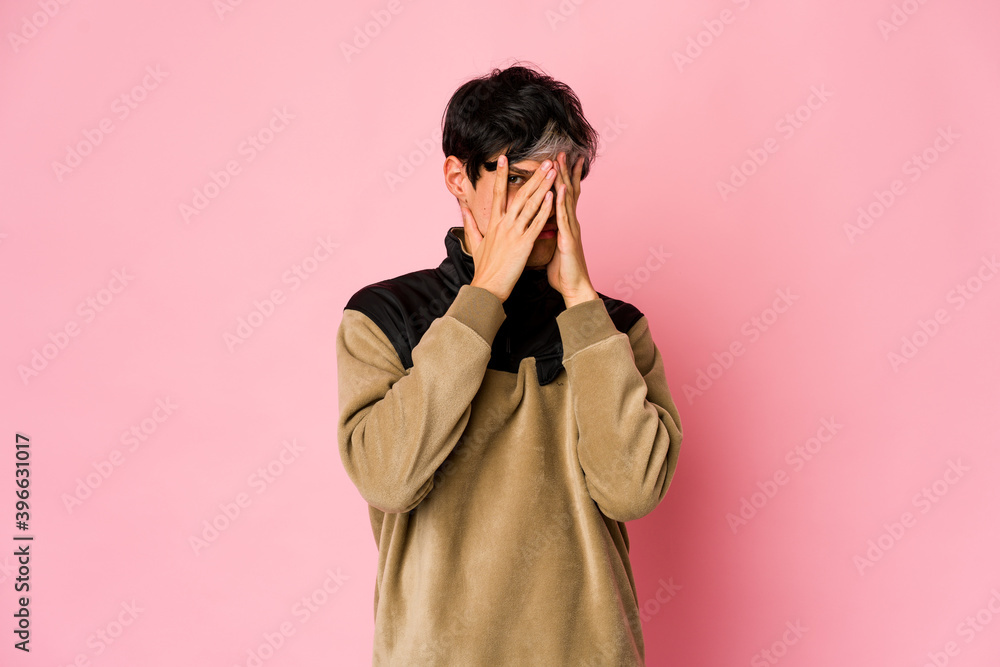 Young skinny hispanic man blink at the camera through fingers, embarrassed covering face. Young skinny hispanic man blink at the camera through fingers, embarrassed covering face.