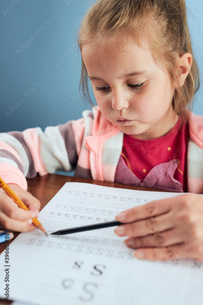 Little girl preschooler learning to write letters with help of her tutor. Kid writing letters doing a school work. Concept of early education Little girl preschooler learning to write letters with help of her tutor. Kid writing letters doing a school work. Concept of early education