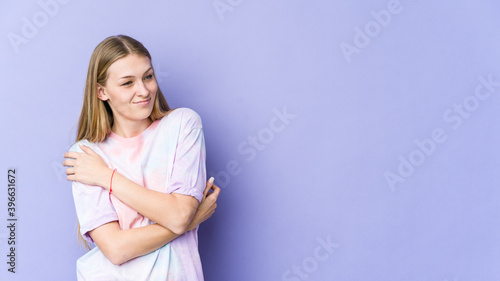Young blonde woman isolated on purple background smiling confident with crossed arms.