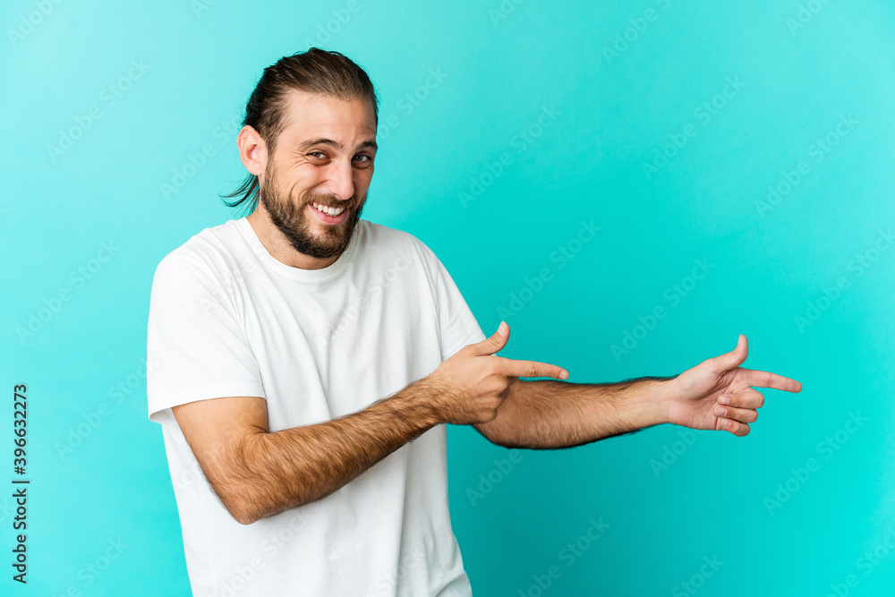 Young man with long hair look pointing with forefingers to a copy space, expressing excitement and desire. Young man with long hair look pointing with forefingers to a copy space, expressing excitement and desire.