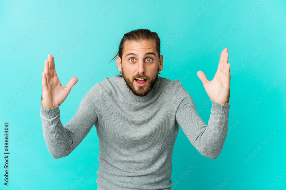 Young man with long hair look receiving a pleasant surprise, excited and raising hands. Young man with long hair look receiving a pleasant surprise, excited and raising hands.