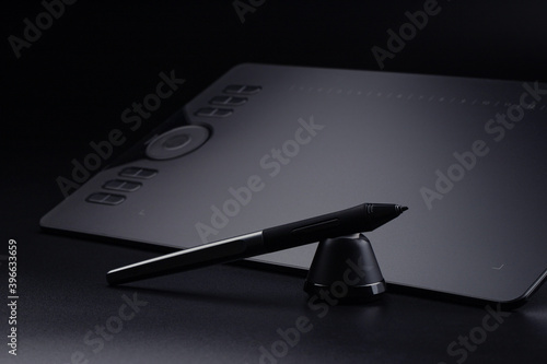 graphic tablet with a stylus and stand on a black background © Елена Челышева