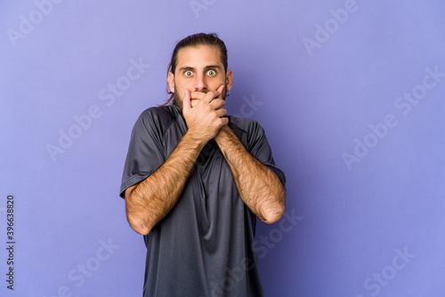 Young man with long hair look shocked pointing with index fingers to a copy space.
