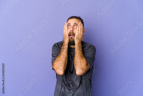 Bild auf Leinwand Young man with long hair look showing fist to camera, aggressive facial expression