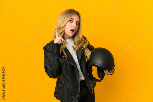 Young blonde caucasian biker woman holding helmet having an idea, inspiration concept.