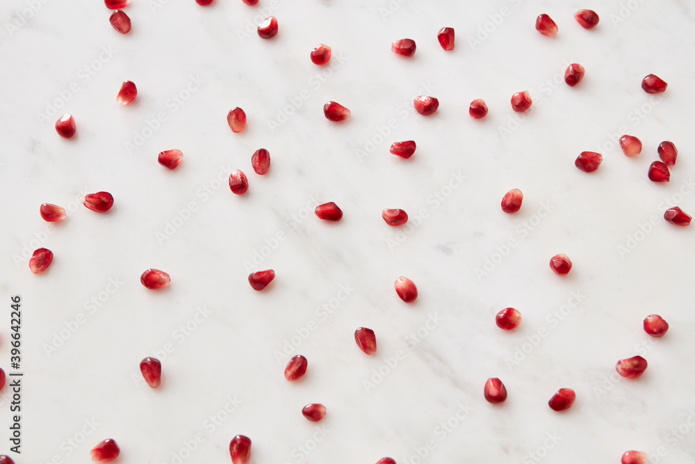 Horizontal pattern from fresh juicy natural pomegranate seeds on a marble background.