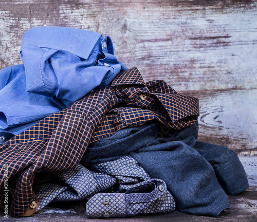 Crumpled men's shirts of different colors lie on the table. Background and texture.