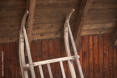 Wooden vintage sleigh leaning against the wall. Rustic barn in alps with retro sled close-up.