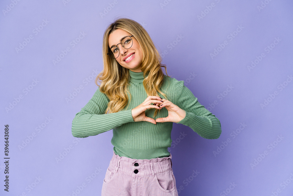 Young caucasian blonde woman smiling and showing a heart shape with hands. Young caucasian blonde woman smiling and showing a heart shape with hands.