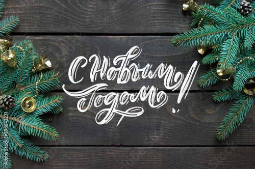 Happy New Year russian chalk hand lettering inscription. Christmas background with tree branches and cones.
