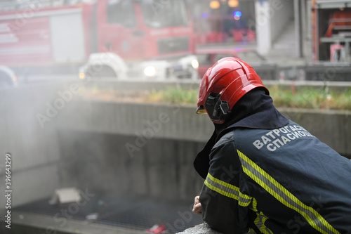 A photo of a firefighter from behind as he rests after putting out a large fire. © Dragan
