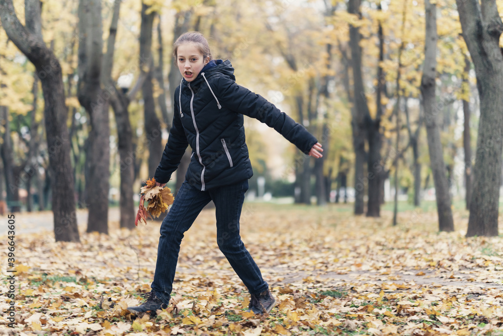 a girl running through the park and enjoys autumn, beautiful nature with yellow leaves