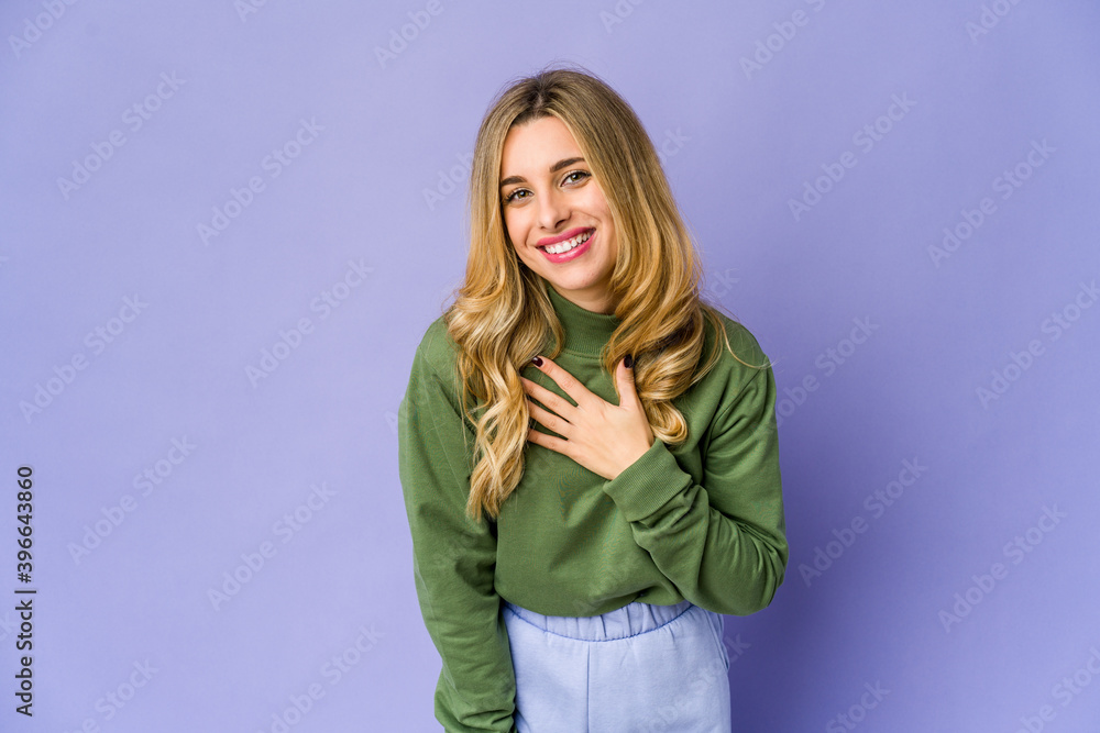 Young caucasian blonde woman laughs out loudly keeping hand on chest. Young caucasian blonde woman laughs out loudly keeping hand on chest.
