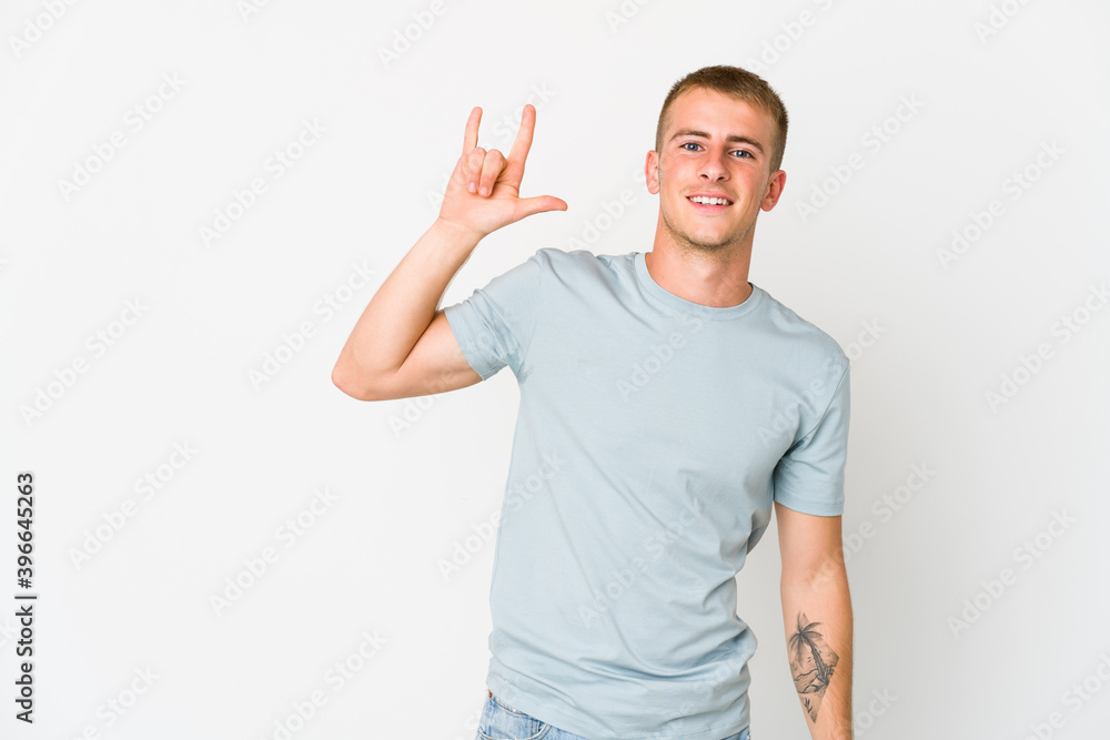 Young caucasian handsome man showing a horns gesture as a revolution concept. Young caucasian handsome man showing a horns gesture as a revolution concept.