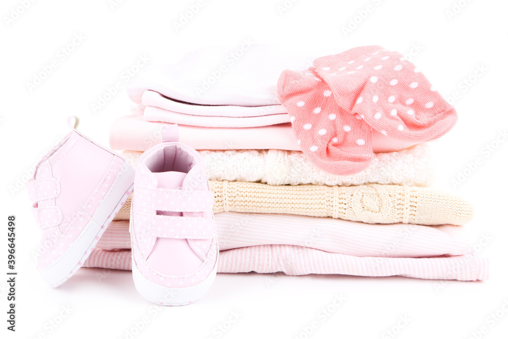 Different folded baby clothes with pair of shoes isolated on white background Different folded baby clothes with pair of shoes isolated on white background