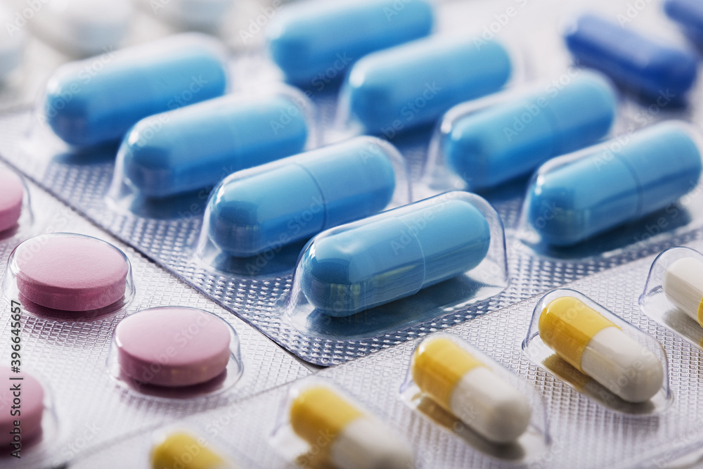 Heap of medical pills in white, blue and other colors. Pills in plastic package. Concept of healthcare and medicine. Heap of medical pills in white, blue and other colors. Pills in plastic package. Concept of healthcare and medicine.