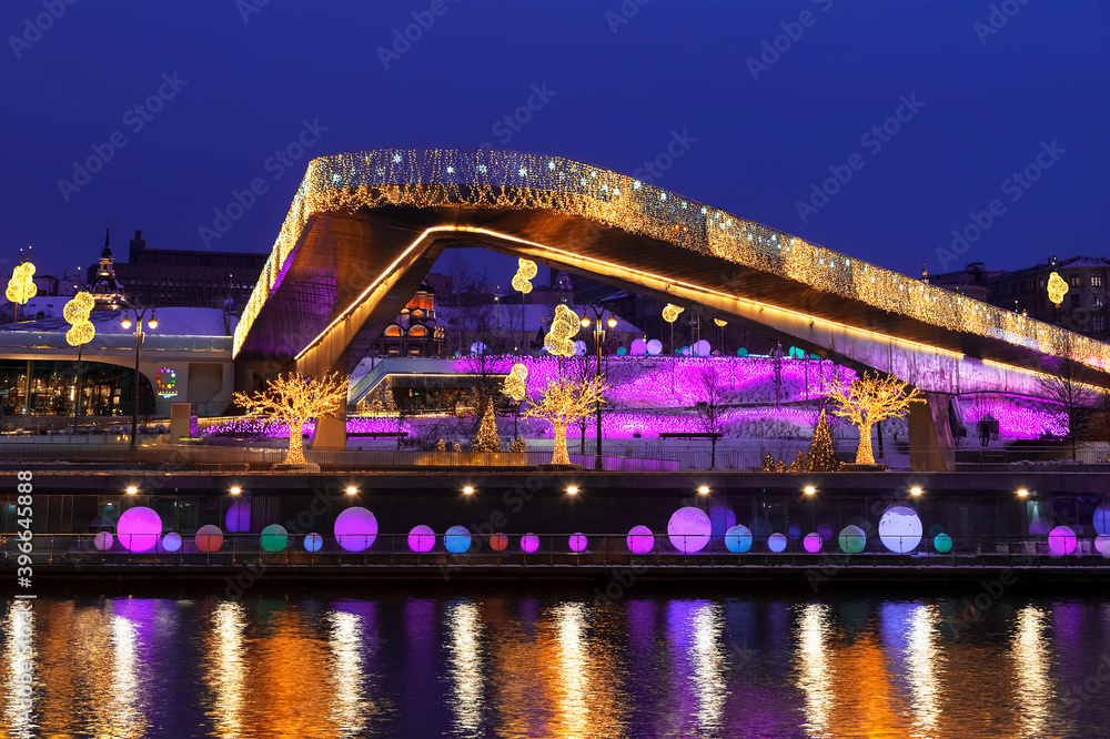 Obraz premium View of Christmas Moscow with a soaring bridge over the Moscow river, new year installations in the form of glowing trees and colorful glowing balls on Moskvoretskaya embankment. Russia