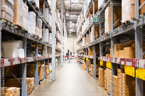 Warehouse interior view, with boxes stacked up high on both sides of an aisle © Sundry Photography