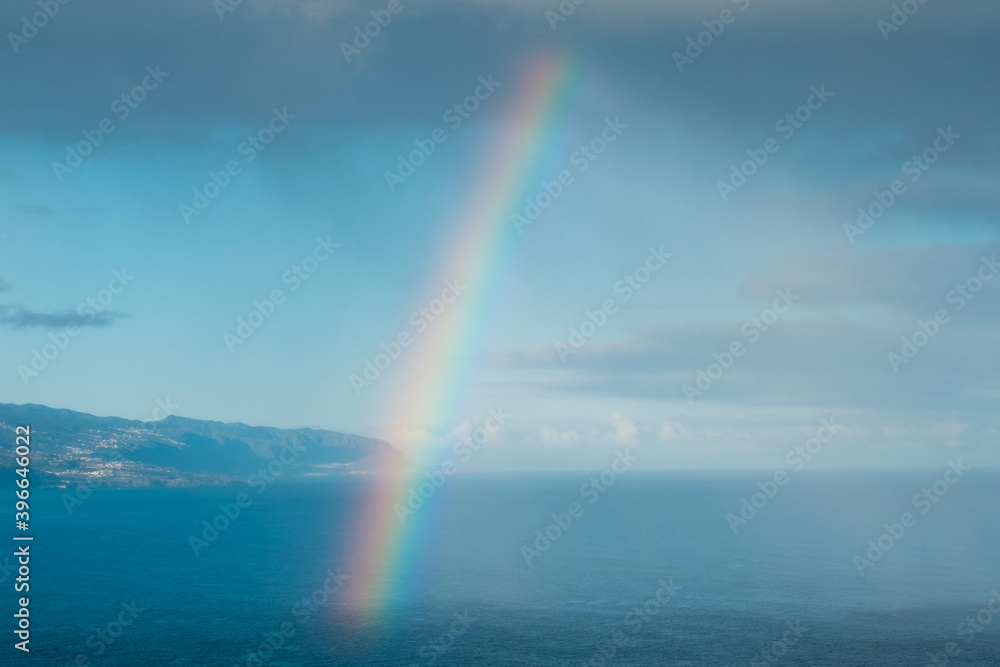 Rainbow coming out of cloud over ocean water