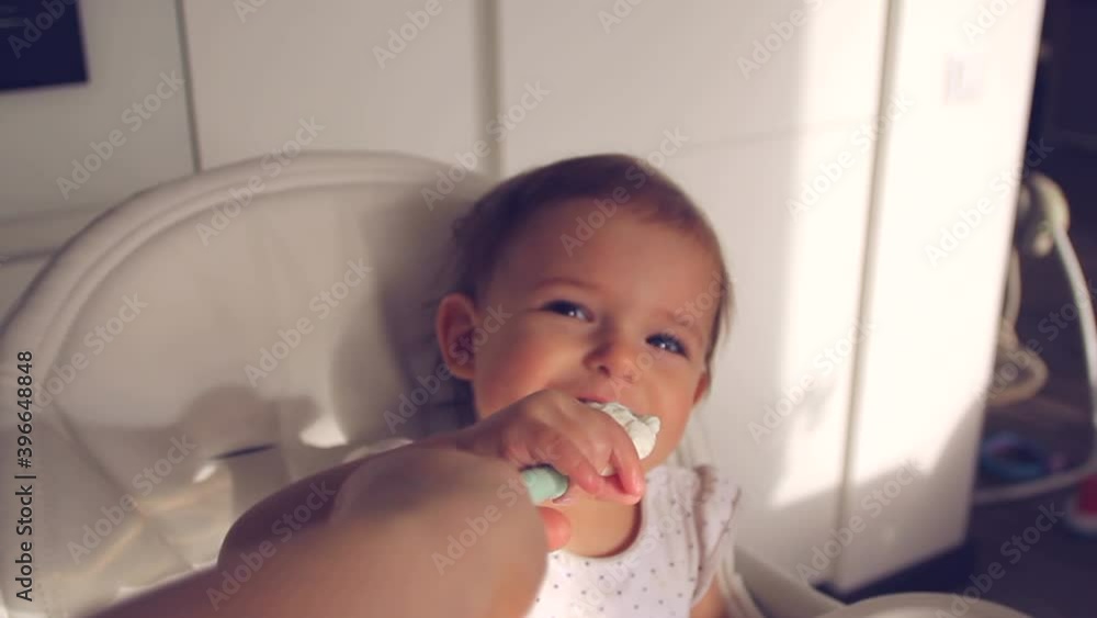Moms Hand giving food to her baby on high chair in home kitchen. Creative point of view shot Moms Hand giving food to her baby on high chair in home kitchen. Creative point of view shot