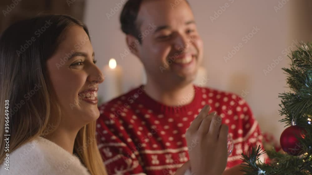 Close Up Shot of Young Couple Decorating a Christmas Tree Together Close Up Shot of Young Couple Decorating a Christmas Tree Together